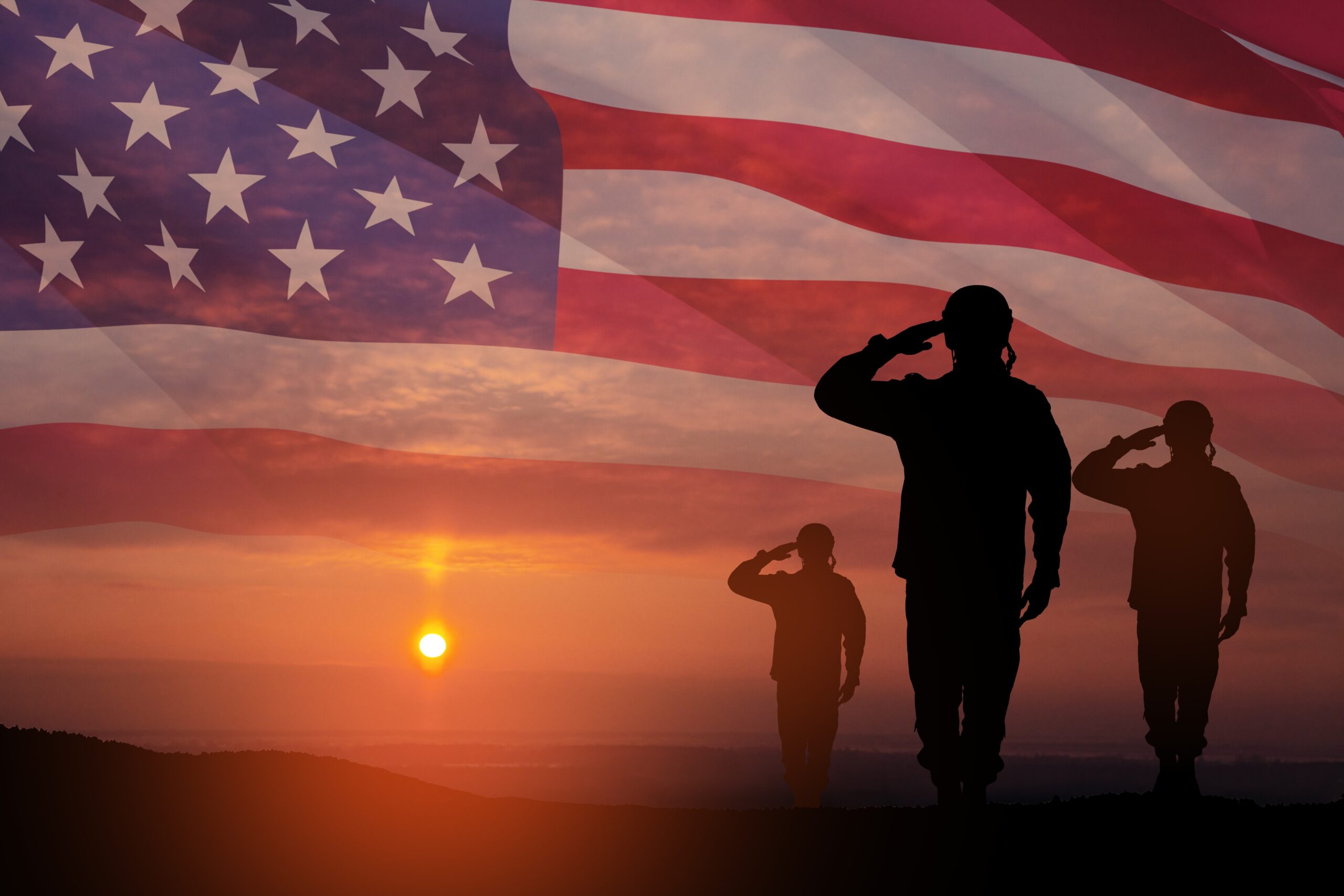 Silhouettes,Of,Soldiers,Saluting,On,Background,Of,Sunset,Or,Sunrise Silhouetted soldiers saluting at sunset with a large American flag blended into the sky background.